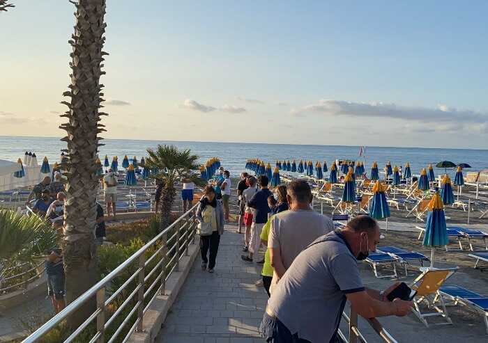 La foto: Liguria, Riviera di Ponente, in fila per un ombrellone